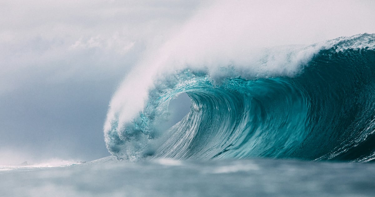 A large turquoise wave curling over as it breaks