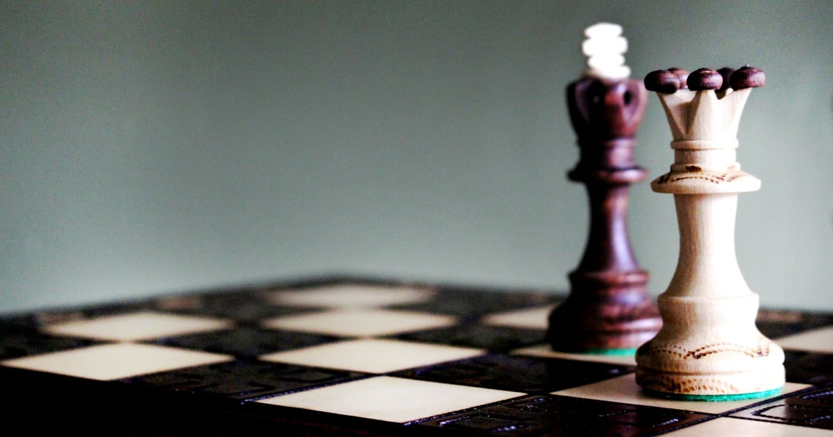 A dark king and a light queen standing side by side on a chessboard