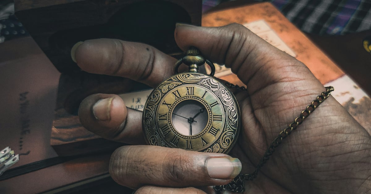 A hand holding an open brass pocket watch