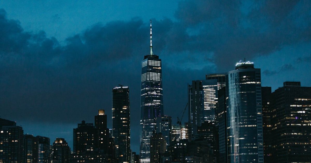 Tall office towers lit up against a dark blue evening sky
