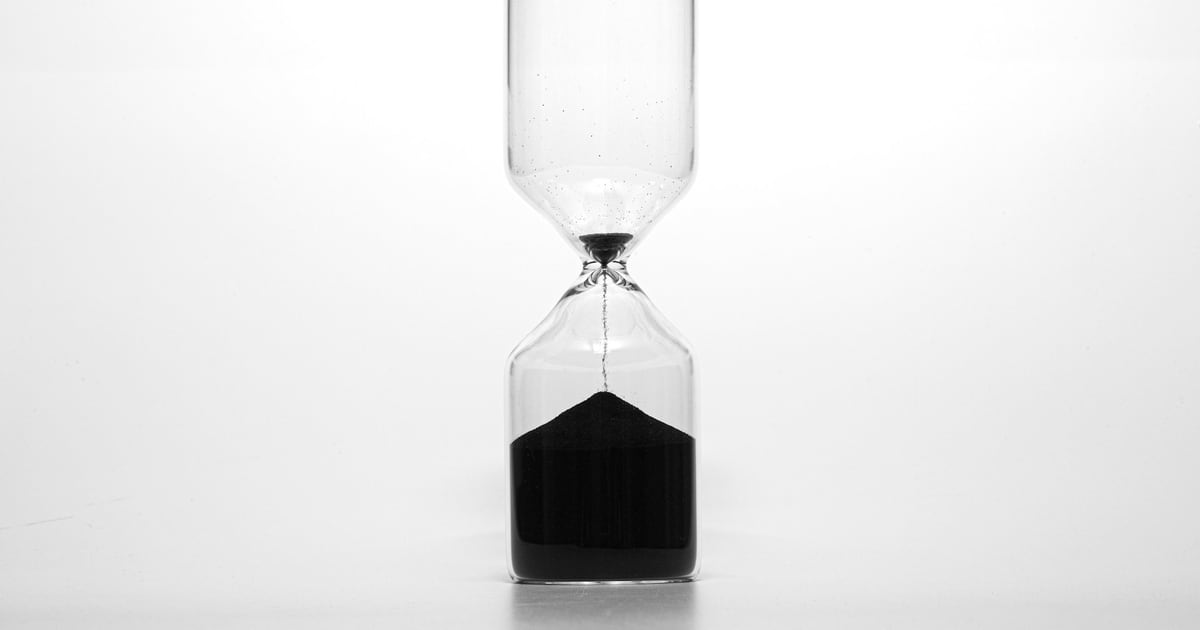 An hourglass with dark sand against a plain white background