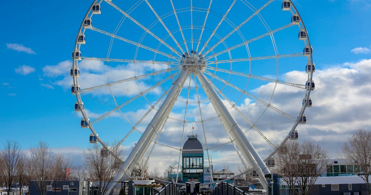 A white Ferris wheel against a blue sky with scattered clouds